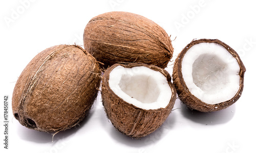Two whole coconuts and two cracked coconut halves isolated on white background