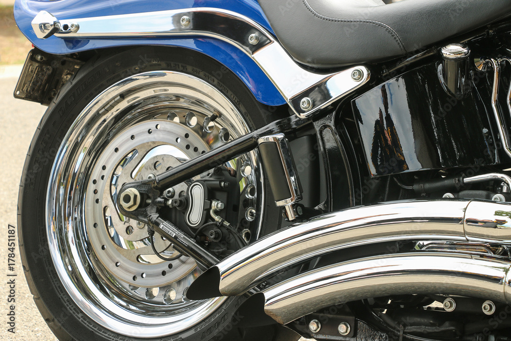 chrome wheel, exhaust and trims of a blue chopper motorcycle chrome wheel, exhaust and trims of a blue chopper motorcycle