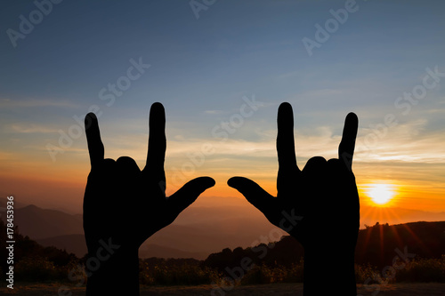Silhouette of hands gesture I love you sign on blurred nature golden sunset background, happy cheerful  life concept