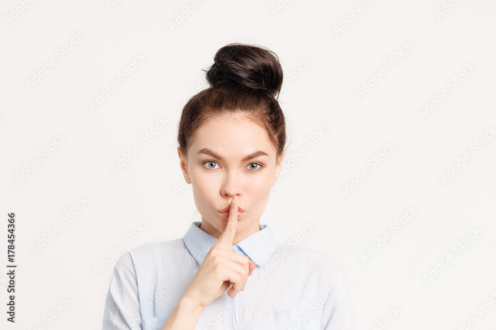 Brunette girl with long hair holds finger near lips . the gesture of silence, mystery, mystery Brunette girl with long hair holds finger near lips . the gesture of silence, mystery, mystery