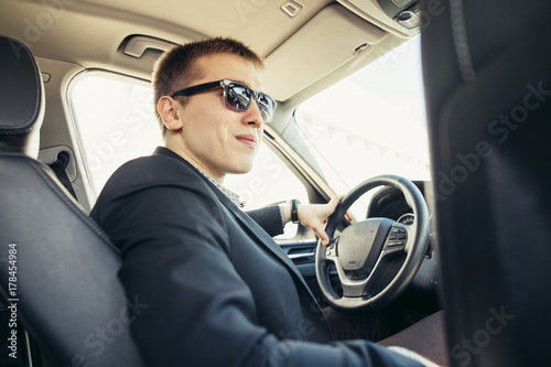 Attractive handsome elegant man in a business suit driving an expensive car photo