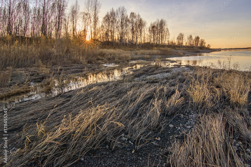Autumn sunset with river, forest and yellow grass. Horizontal background