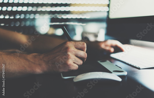 Close up photo of male hands during using a drawing tablet. Graphic designer is drawing pictures by a digital pen and tablet. Professional web illustrator is working with stylus and graphic pad.