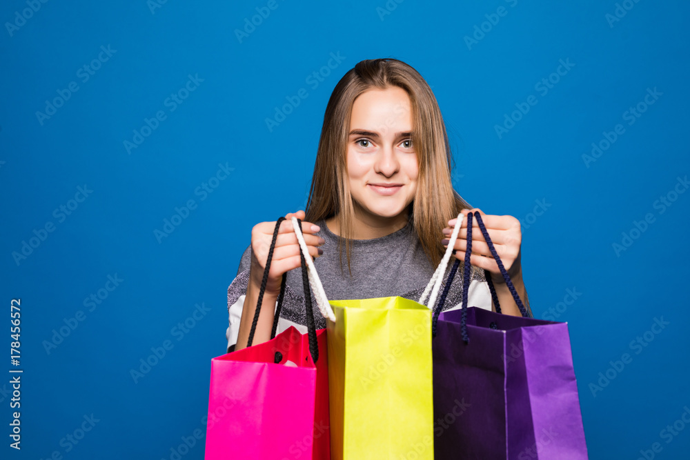 beautiful young woman with colored shopping bags over blue background