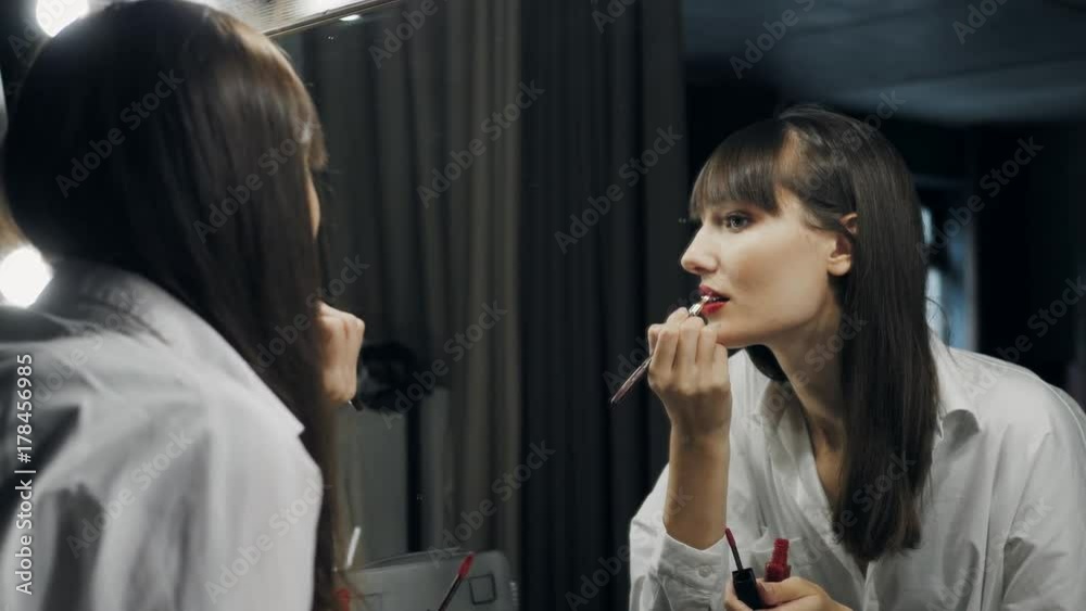 Beautiful attractive woman make up herself in front of the mirror get ready for photoshot and wink her eye to camera Beautiful attractive woman make up herself in front of the mirror get ready for photoshot and wink her eye to camera