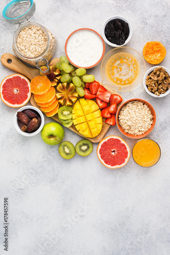 Above view of healthy breakfast with oats, variety of fruits, strawberries, mango, grapes, served on the white table, selective focus