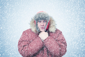 Frozen man in winter clothes warming hands, cold, snow, blizzard