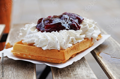 The Belgian wafer. Delicious Belgian waffle with cream, fruit and sauce looks beautiful in the window of the Brussels confectionery store.