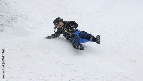 A boy, a child is riding from a snow-capped hill, in winter