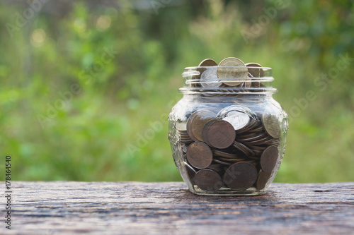 Coins in glass and stack coins with tree for business and tax season.