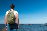 A tourist guy with a backpack on the Baltic Sea coast near Tallinn enjoys nature in Estonia. Travel, adventure.