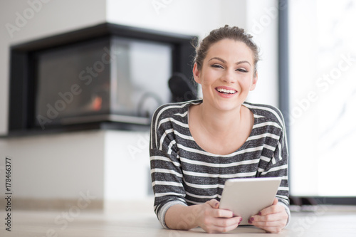 woman using tablet computer in front of fireplace