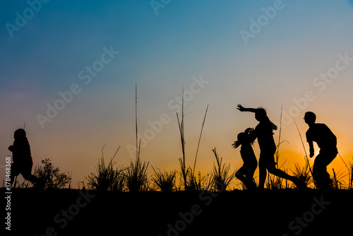 The children are running on the meadow at sunset.