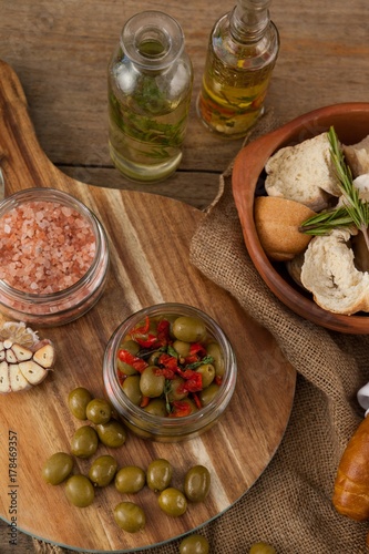 Olives and spices with bread in container by oil bottles