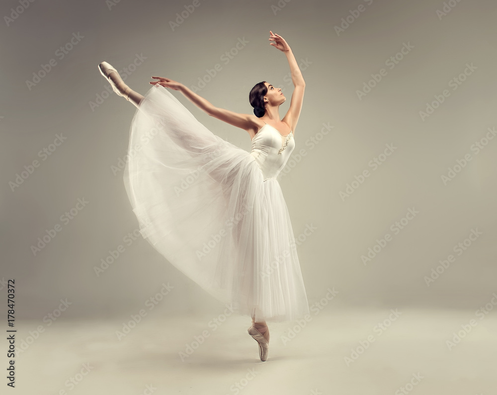Obraz premium Ballerina. Young graceful woman ballet dancer, dressed in professional outfit, shoes and white weightless skirt is demonstrating dancing skill. Beauty of classic ballet.