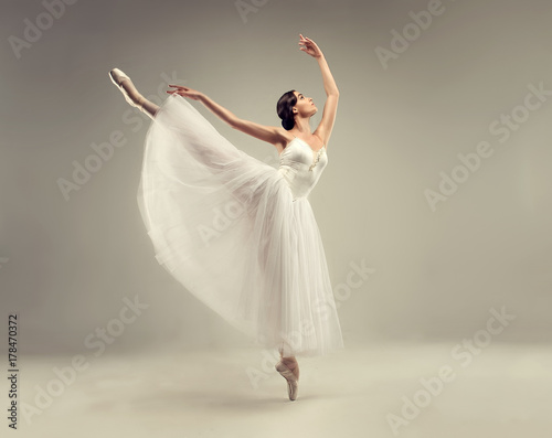 Ballerina. Young graceful woman ballet dancer, dressed in professional outfit, shoes and white weightless skirt is demonstrating dancing skill. Beauty of classic ballet.
