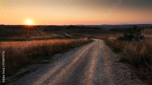 strada sterrata con a fianco campi di grano e cielo al tramonto