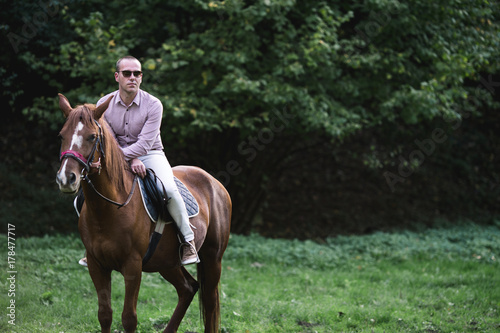 Elegant casually dressed man riding a horse