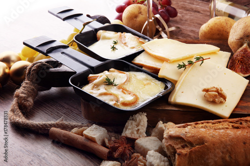 Delicious traditional Swiss melted raclette cheese on diced boiled or baked potato served in individual skillets