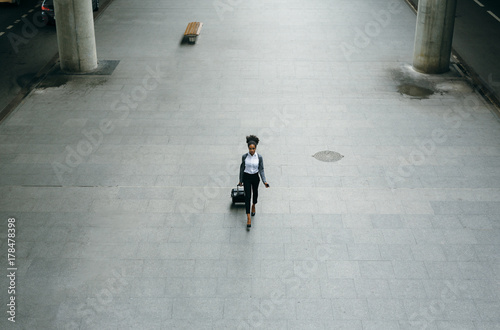 High angle view of young businesswoman walking on the sidewalk to a taxi