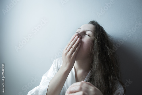 Young woman yawing, looking tired after work, working hard