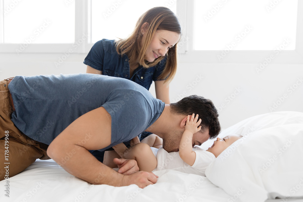 Young parents playing with baby on bed Young parents playing with baby on bed