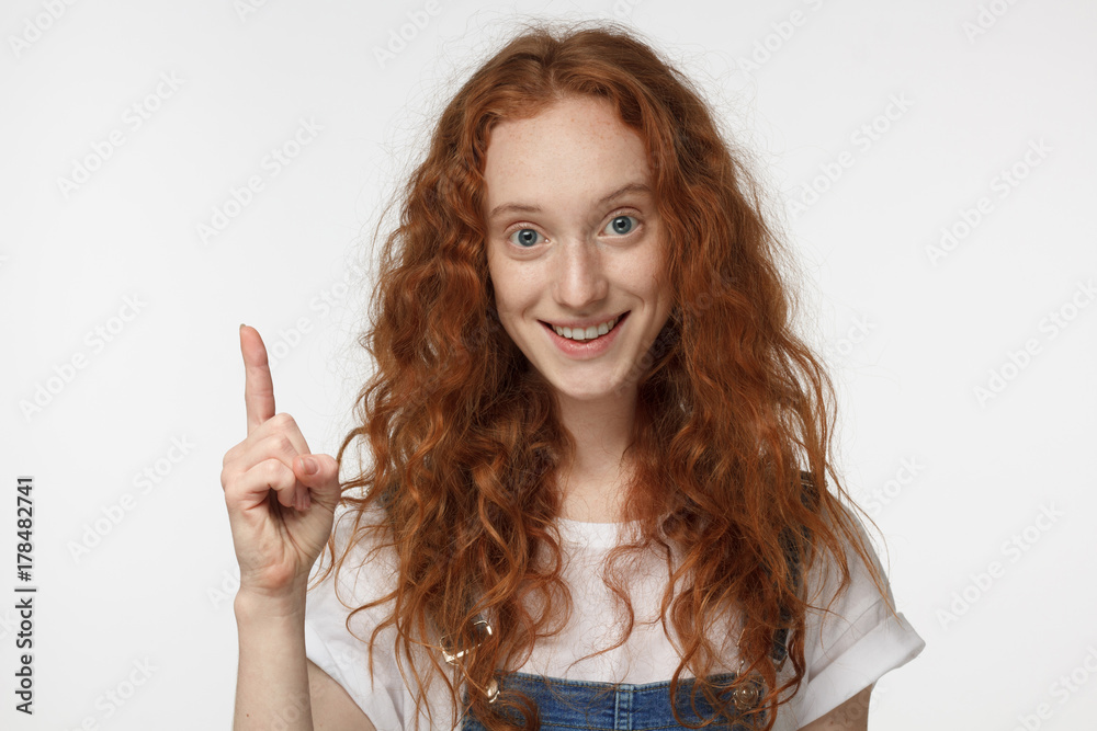 I have an idea! Beautiful redhead girl keeping finger pointed upwards, showing something above her head, making gesture with index finger. Eureka, solution sign concept I have an idea! Beautiful redhead girl keeping finger pointed upwards, showing something above her head, making gesture with index finger. Eureka, solution sign concept