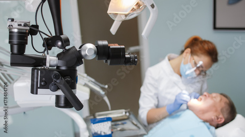 Photos dentist treats a patient in his office with a modern microscope