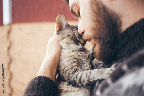 Cat and man, portrait of happy cat with close eyes and young man, people playing with the kitten. Handsome Young Animal-Lover Man, Hugging and Cuddling his Gray Domestic Cat Pet photo