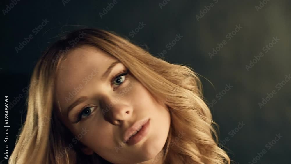 Sensual close-up portrait of beautiful blonde woman with curly gold hair posing on black background in studio Sensual close-up portrait of beautiful blonde woman with curly gold hair posing on black background in studio