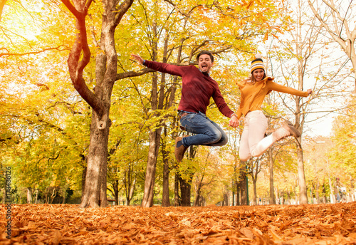 Happy couple jumping in a park in autumn