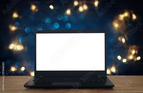 open laptop with white screen on wooden table in front of abstract glitter background