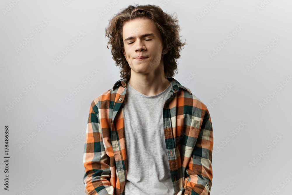 Negative human emotions, annoyance and irritation concept. Enraged annoyed furious young European man with curly hair closing eyes counting up to ten and breathing deeply, trying to calm down Negative human emotions, annoyance and irritation concept. Enraged annoyed furious young European man with curly hair closing eyes counting up to ten and breathing deeply, trying to calm down
