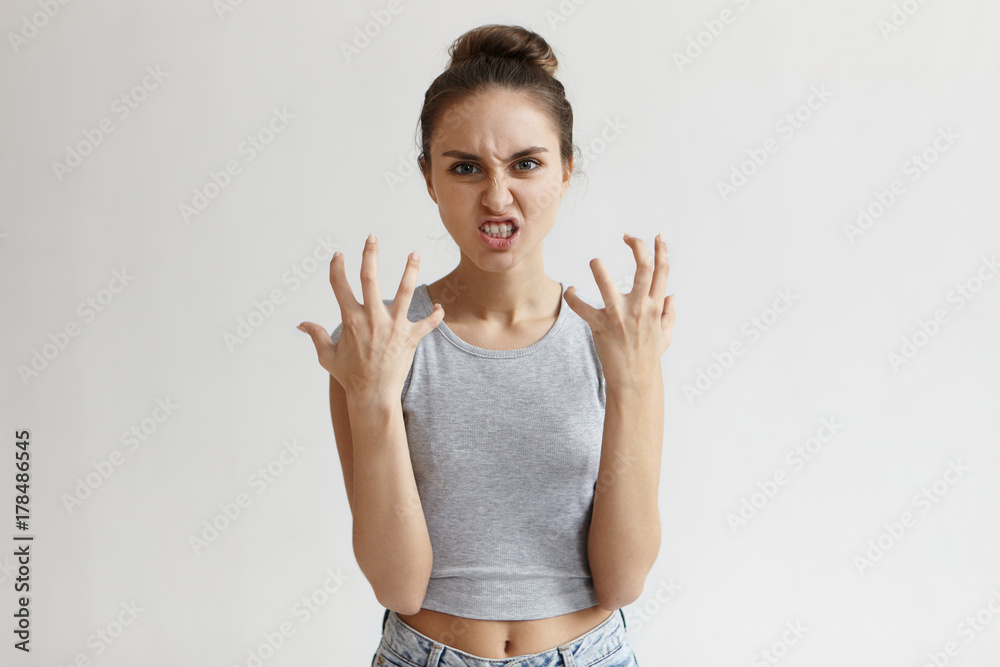 Picture of enraged dissatisfied young female grimacing, clenching teeth