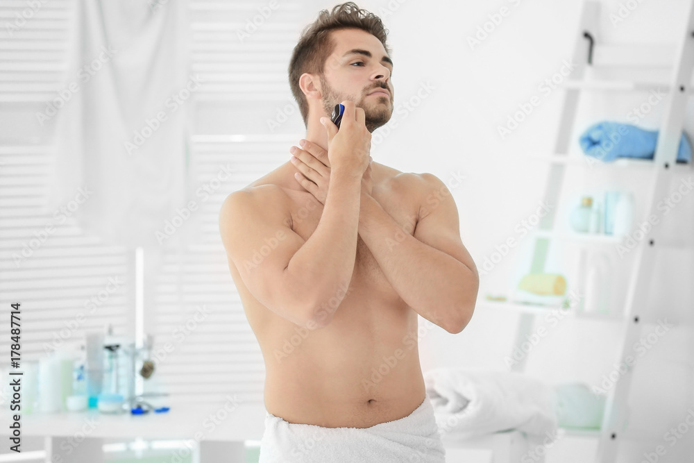 Handsome young man shaving in bathroom Handsome young man shaving in bathroom