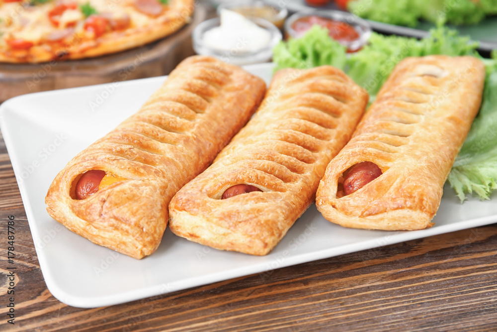 Plate with tasty sausage rolls on wooden table Plate with tasty sausage rolls on wooden table