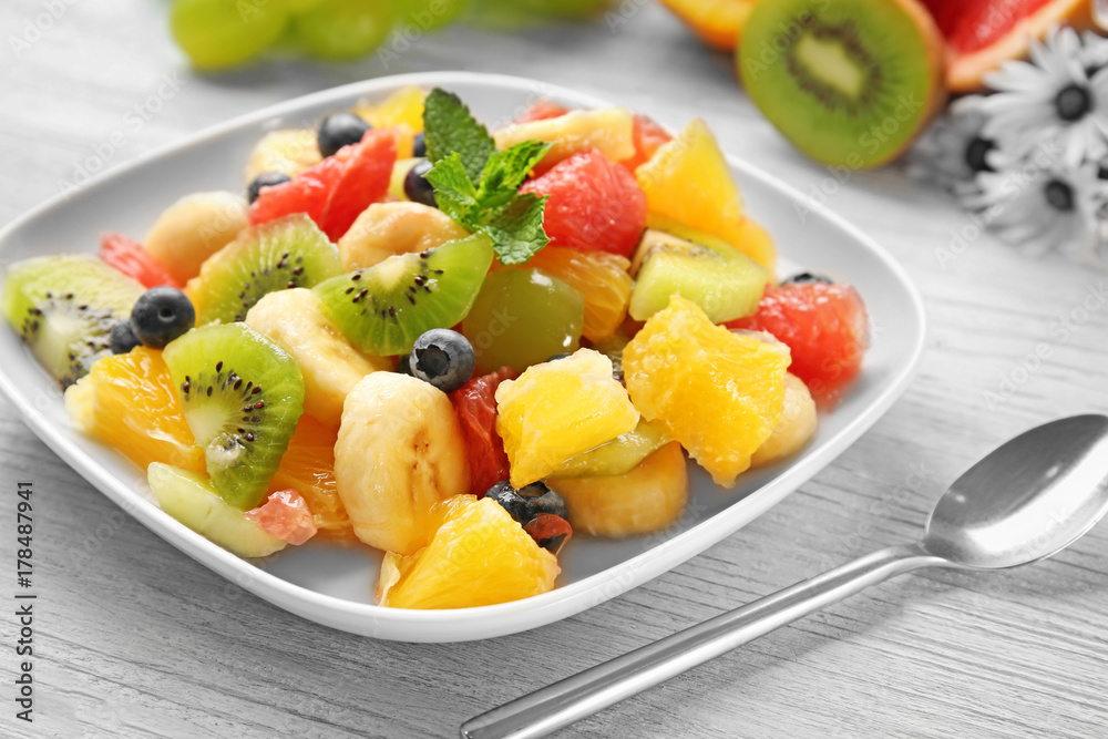 Plate with delicious fruit salad on wooden table Plate with delicious fruit salad on wooden table