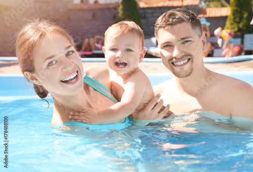 Child swimming lesson. Cute little boy learning to swim with parents in pool