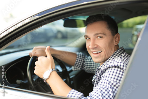 Happy man sitting in car and showing thumb up