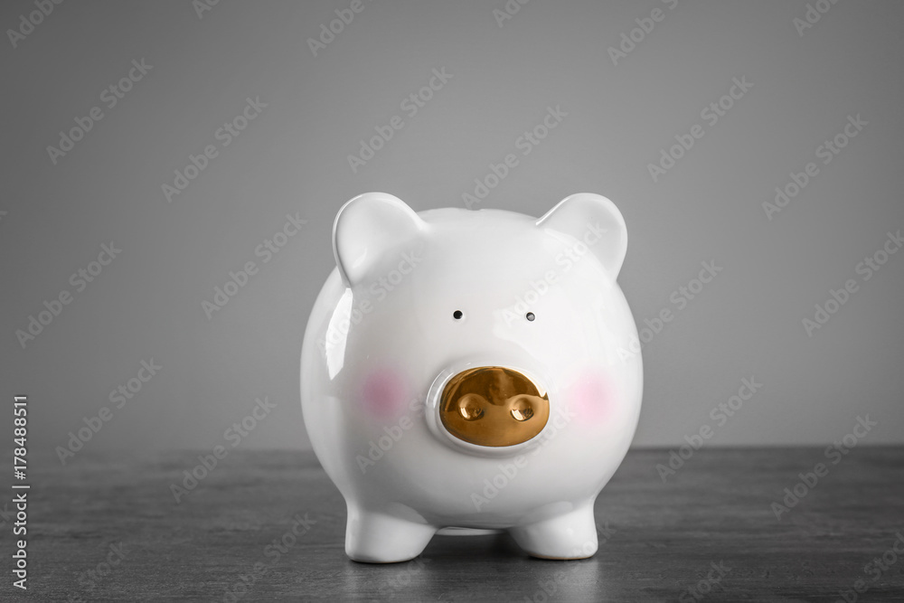 Cute piggy bank on table against grey background Cute piggy bank on table against grey background