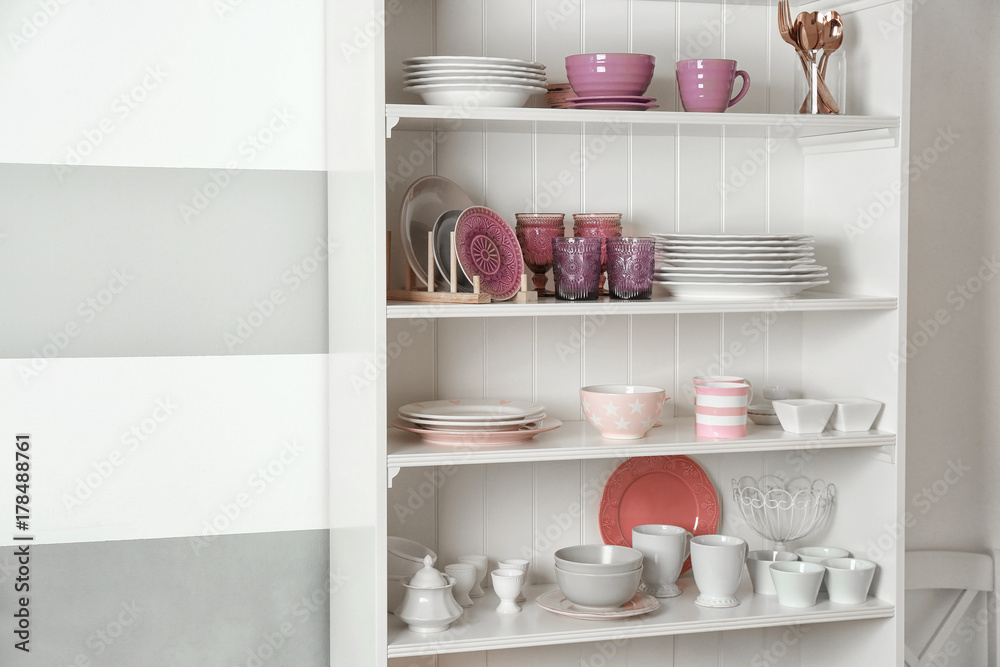 Kitchen shelving with dishware on color wall background Kitchen shelving with dishware on color wall background