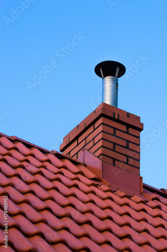 Dom jednorodzinny, dach z czerwonej dachówki, komin z wkładem kominowym. 