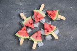 Slices of ripe watermelon and ice cubes on gray background