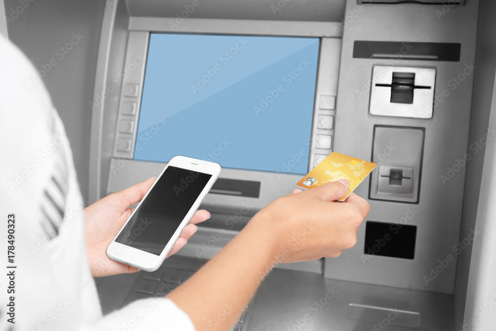 Woman with credit card and cell phone near cash machine, closeup Woman with credit card and cell phone near cash machine, closeup