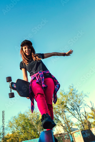 Cute urban girl holding skateboard in skatepark