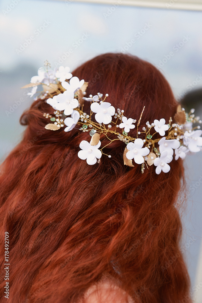 Naklejka premium Beautiful red-haired girl with long curly hair in the bride, in a long lace dress. A natural beauty.