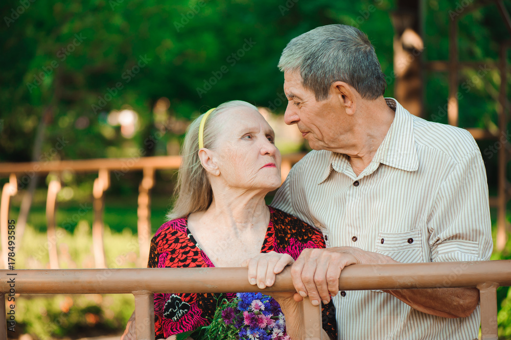 Embrace and kiss of old couple in a park on a sunny day Embrace and kiss of old couple in a park on a sunny day
