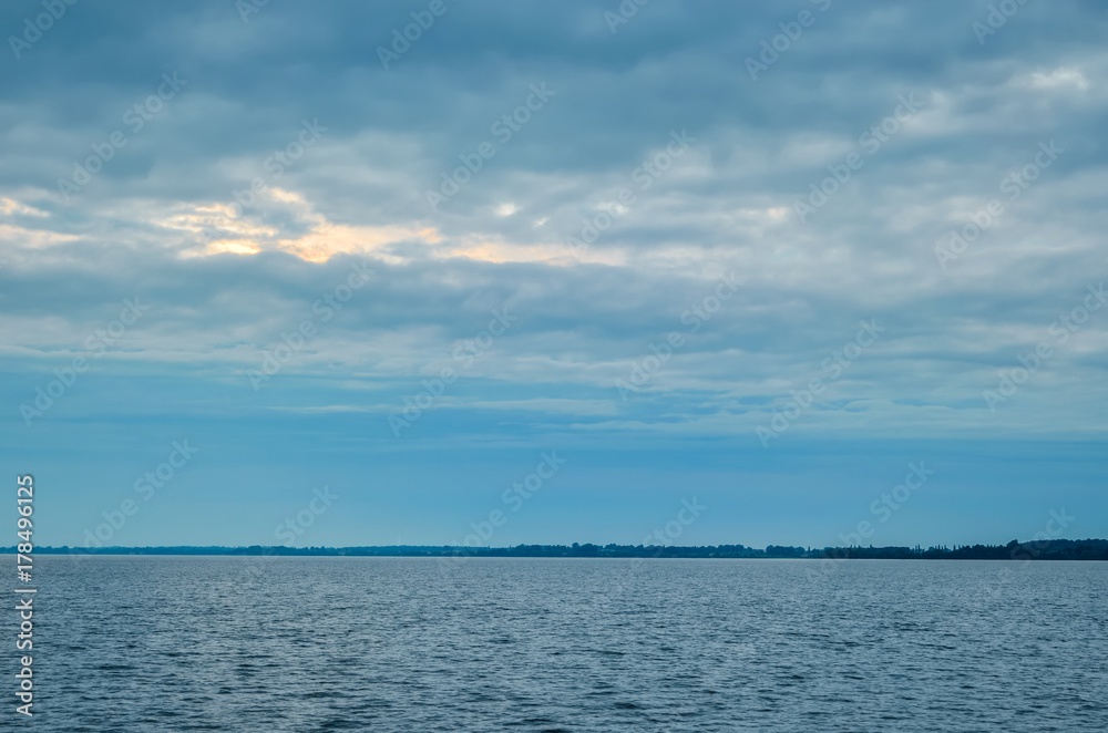 Minimalist summer landscape. Large lake with coastline on a cloudy day.