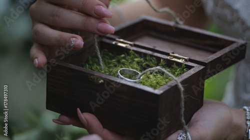 Groom holds a jewelry gift box with gold wedding rings. man's hand takes wedding ring from wooden box