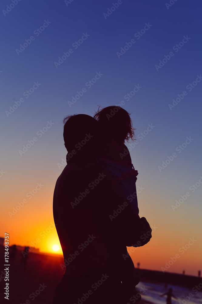 Back side view silhouettes of father and little baby playing at sunset background